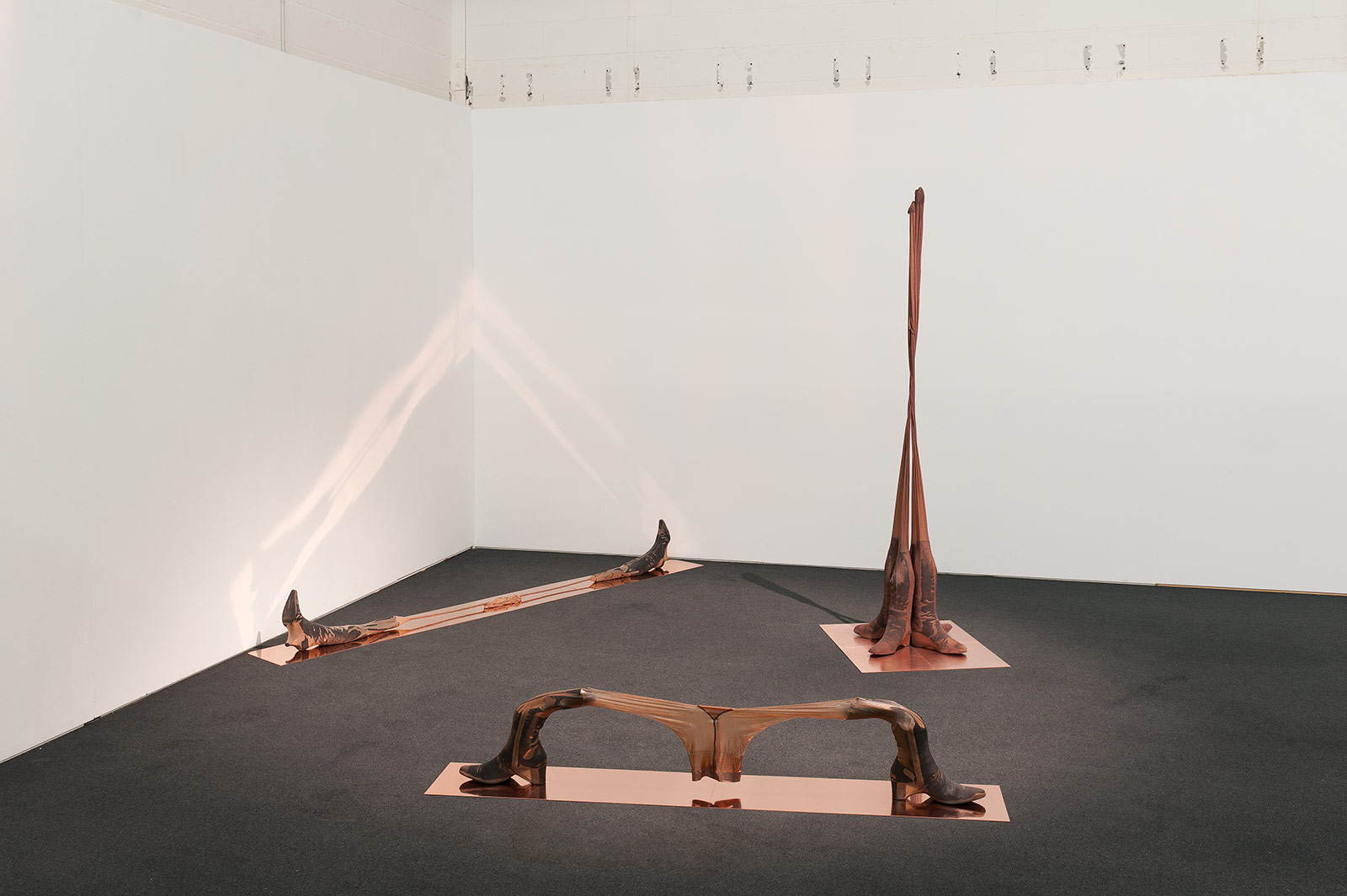 Installation view of three sculptures made of tights and epoxy resin on copper plates