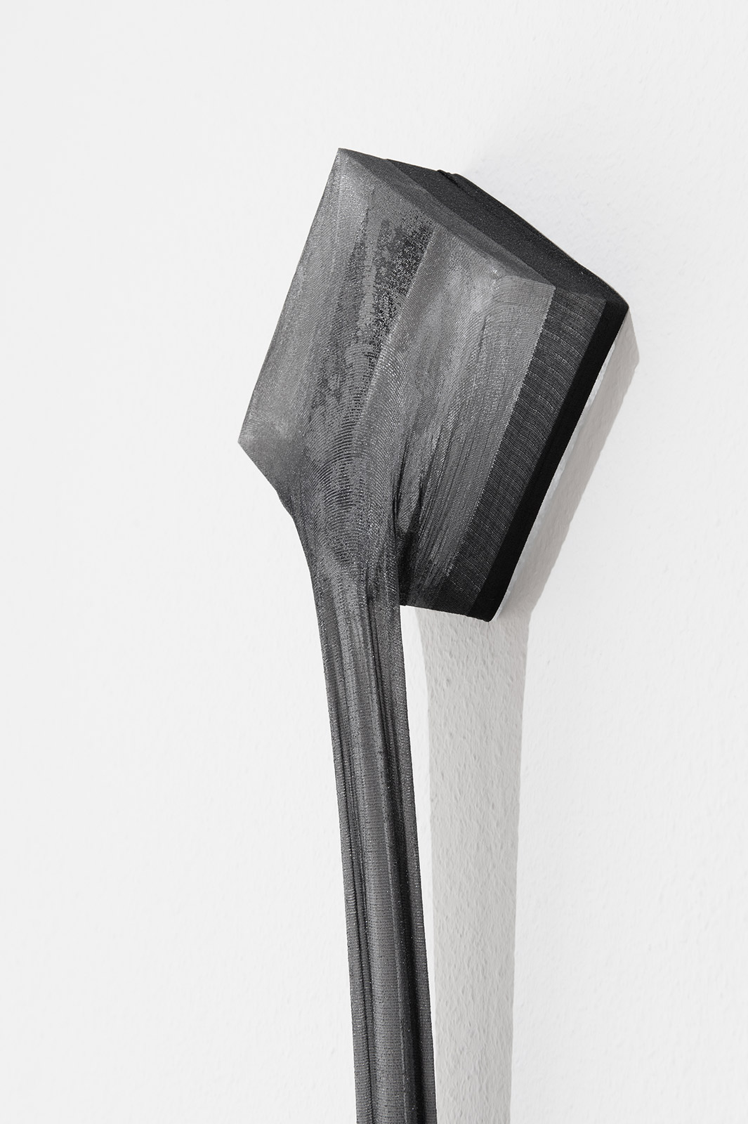 Detail view of an art object made from a stretched black polyamide stocking and epoxy resin